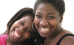 two smiling women heads touching